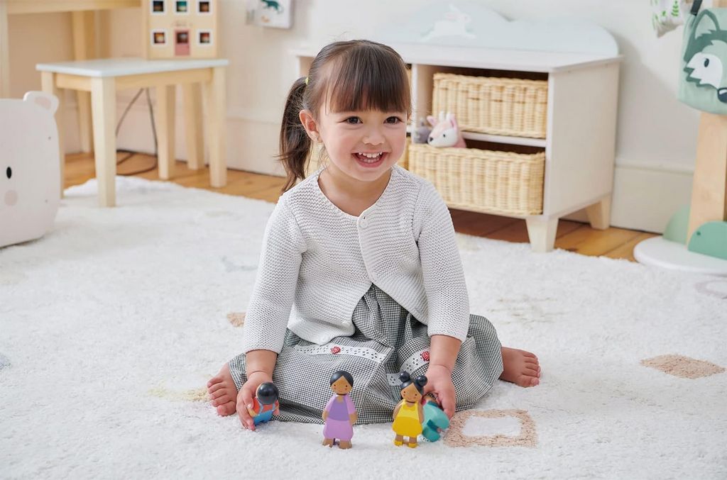 A young girl playing with a Black Dollhouse dolls set
