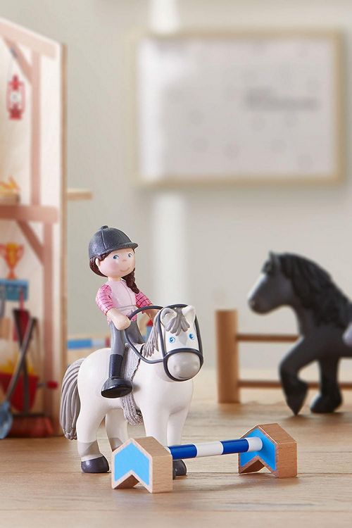 Toy horse and rider set on a wooden floor with a blurred background