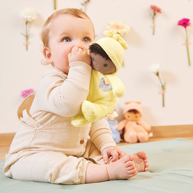A baby holding the soft black baby's first doll