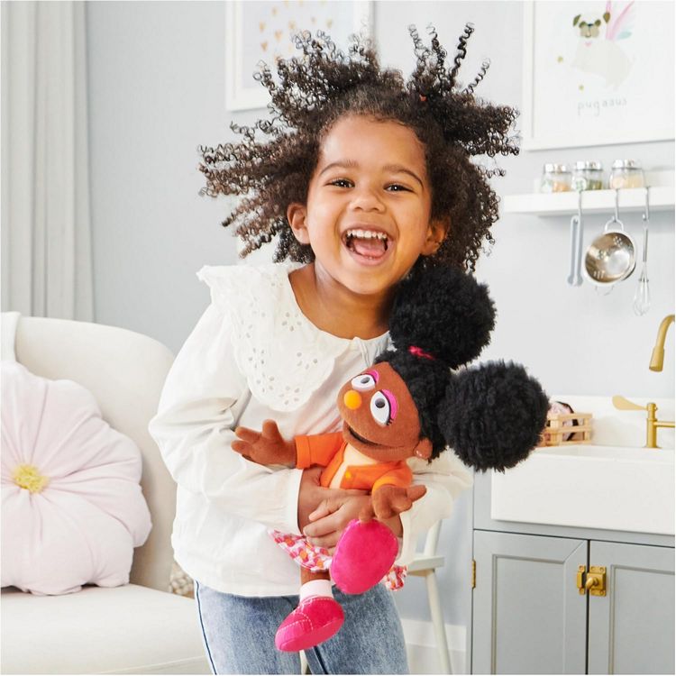 A young child holding a plush Sesame Street Gabrielle toy
