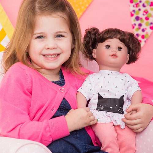 A little girl holding Kitty Kisses Cuddle & Coo interactive crybaby doll by Adora