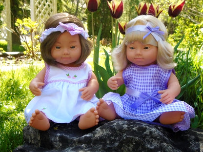 comparison of two down syndrome girl dolls from miniland, one blonde, one brunet