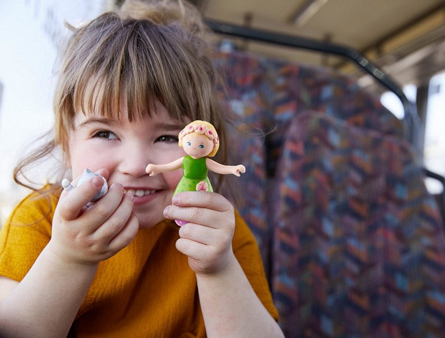 Showing a young toddler with a HABA dollhouse doll in her hand for scale