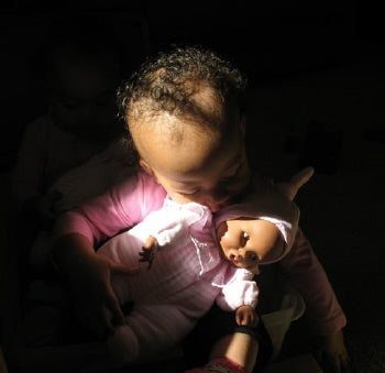 a Young black girl cuddling with her black baby doll