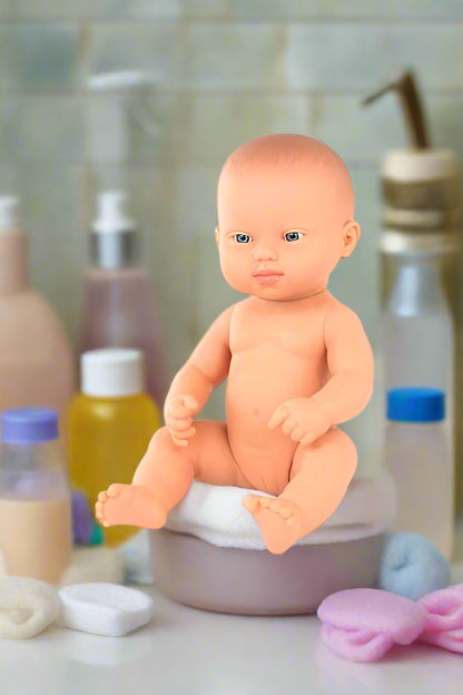 Anatomically correct naked Down syndrome baby doll sitting on a towel in a bathroom setting