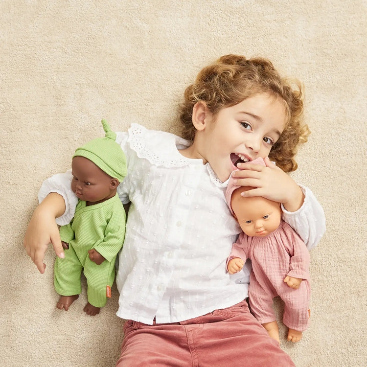 Child holding two down syndrome baby dolls, one black and one white, on a beige carpet.
