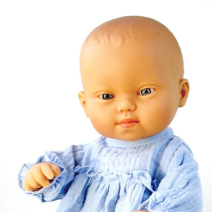 Close up portrait of a Down Syndrome Baby Doll wearing a blue outfit on a white background