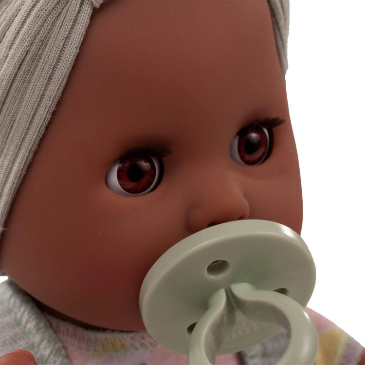 Close-up of a black baby doll with a pacifier and headband on a white background