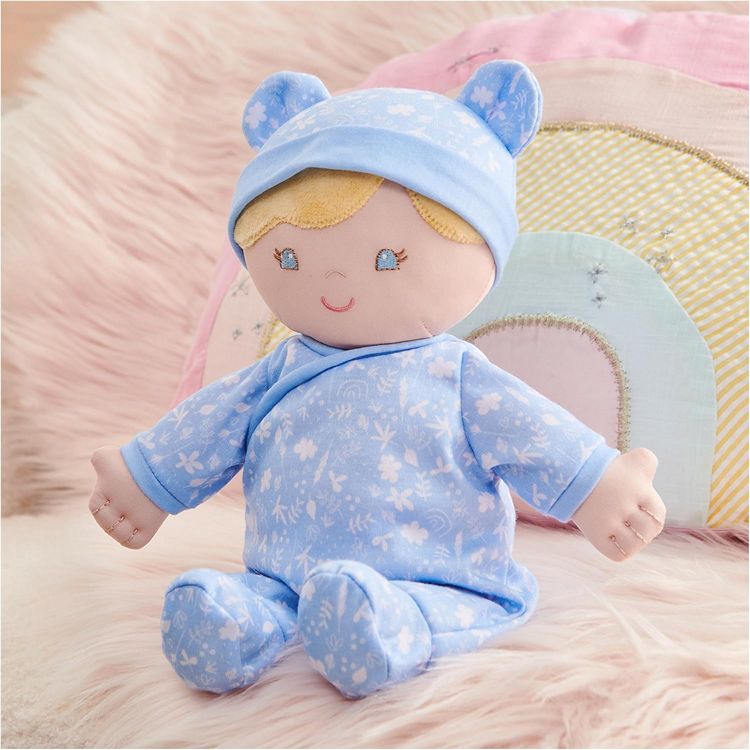 Stuffed doll in blue outfit and hat on a soft surface