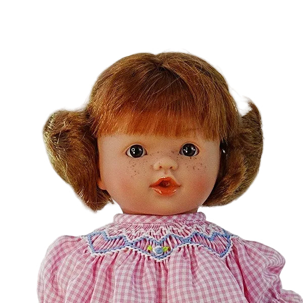 close up portrait of a cute life like redhead doll with brown eyes and freckles  showing her hand smocked and embroidered collar