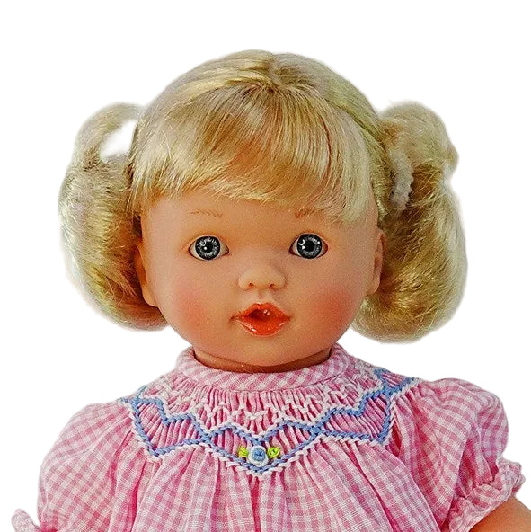 close up portrait of blonde blue eyes doll and the embroidered smocked collar of her dress.