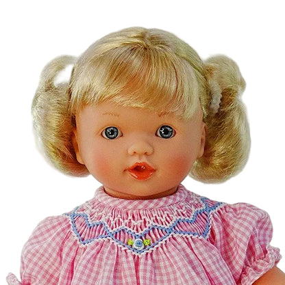 close up portrait of blonde blue eyes doll and the embroidered smocked collar of her dress.