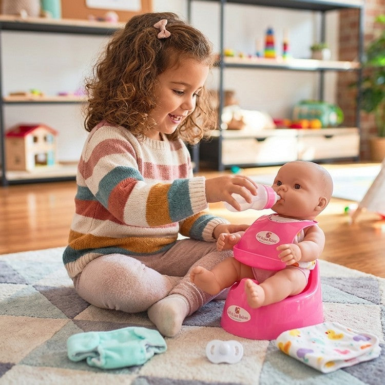 A young girl feeding a bottle to her JC toys potty training doll 