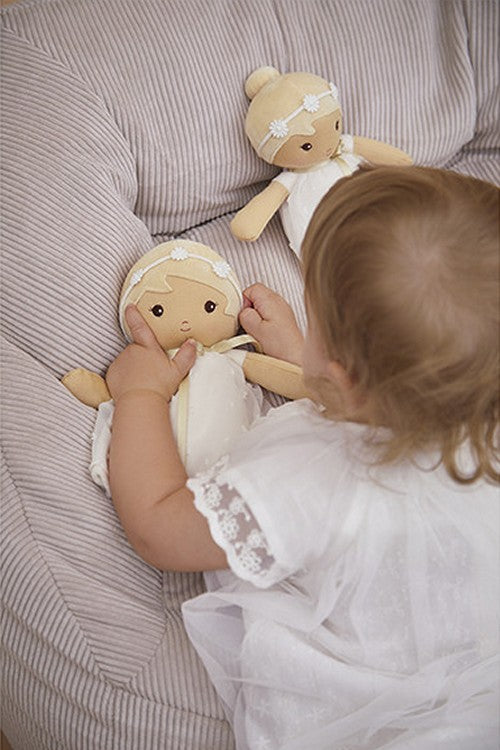 Toddler playing with soft white Kaloo Daphne doll