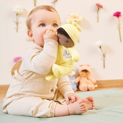 A baby holding the soft black baby's first doll 