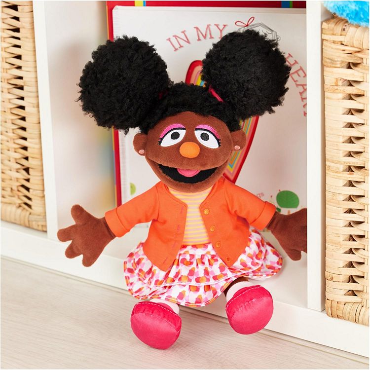 A picture of sesame street Gabrielle  soft plush character doll posed on a bookshelf