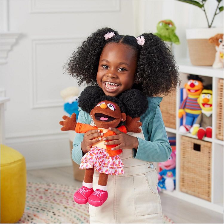 A young black girl holding a Gabrielle doll, the black girl character from Sesame Street