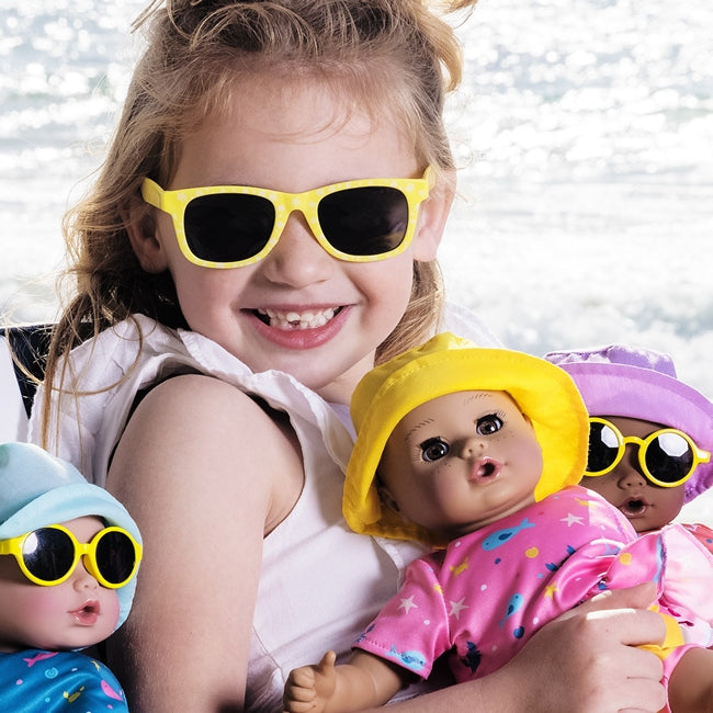A Child model holding three of Adora Dolls Beach Babies Water Play Baby Dolls