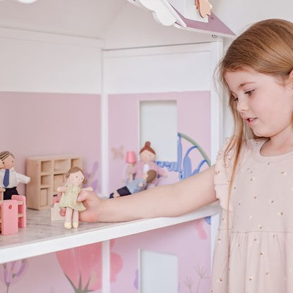 a young girl playing with dollhouse dolls in a doll house