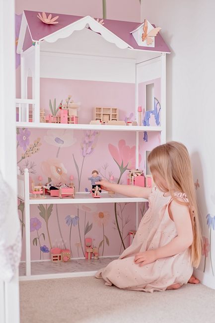a young girl playing with her dollhouse dolls in a doll house