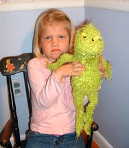 a young girl giving her best 'Grinch' face while holding her Grinch doll