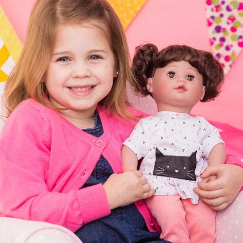 A little girl holding Kitty Kisses Cuddle & Coo interactive crybaby doll by Adora