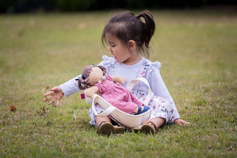 a young girl playing with an ethnic rag doll by Bonikka