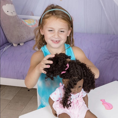 A young girl playing with a black hair styling doll