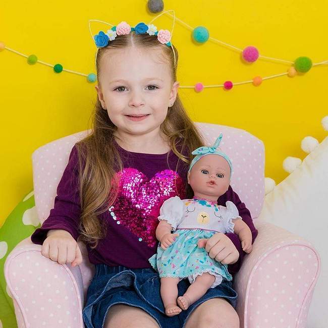 Young girl holding her playtime baby doll by Adora