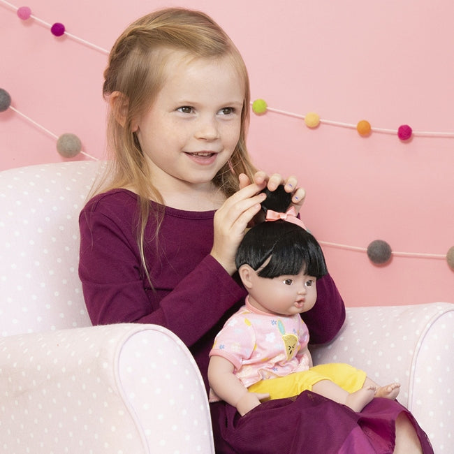 A Little girl holding our Asian Baby doll for size comparison